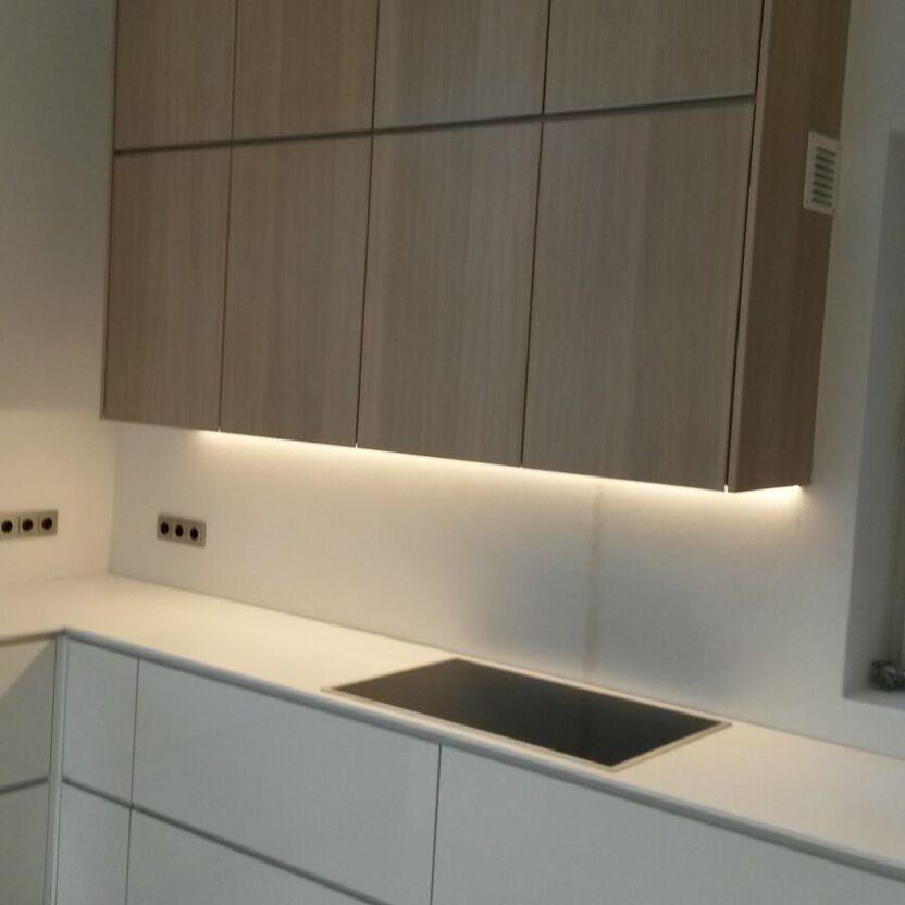 Moderne Einbauküche mit Oberschränken Helle Küche mit Holzoberschränken, Induktionskochfeld und Unterbauleuchten