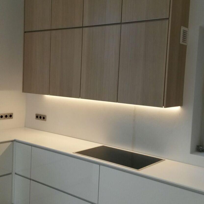 Helle Küche mit Holzoberschränken, Induktionskochfeld und Unterbauleuchten