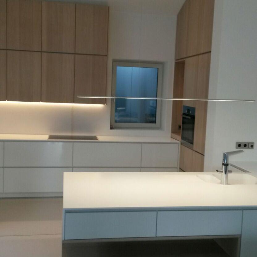 Offene Designküche mit Kochinsel Helle Designküche mit Kochinsel, Oberschränken in Holzoptik und modernem Fenster