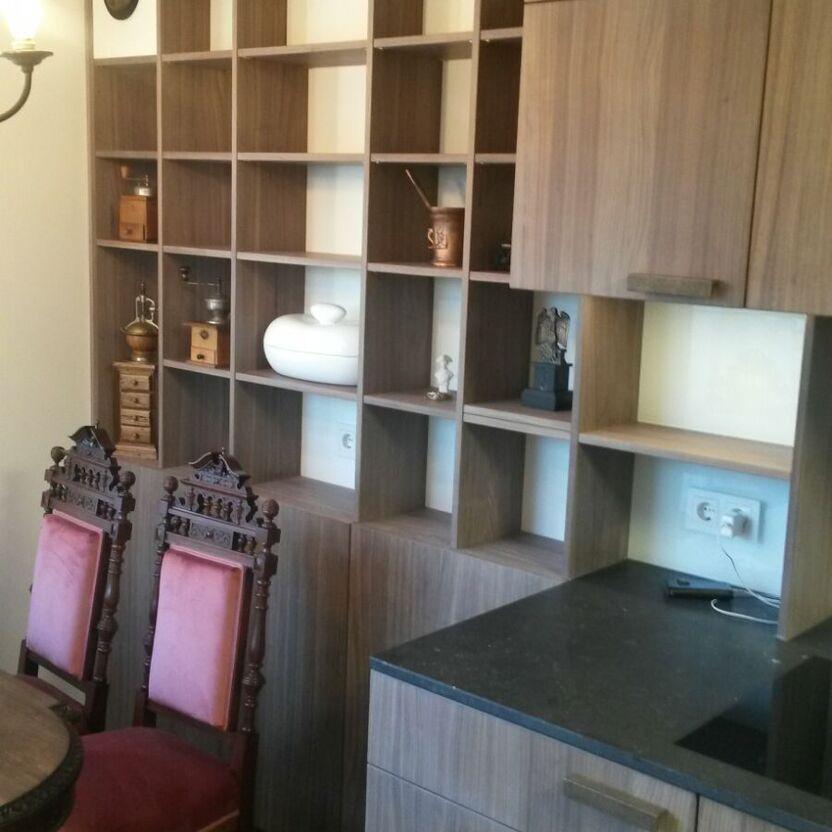 Küche mit Regalwand und Sitzbereich Offene Regalwand in Holzoptik neben antiken Stühlen und schwarzer Arbeitsplatte