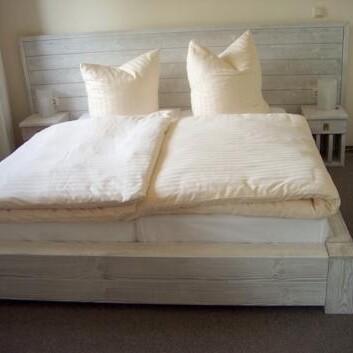 Doppelbett in Weißholz-Optik Weiß lasiertes Holzbett mit hohem Kopfteil, beiger Bettwäsche und Nachttischen