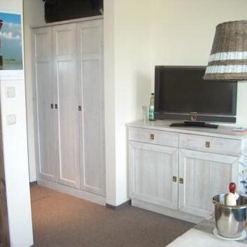 Schrank und TV-Kommode in Weiß Weiß lasierte Holzmöbel mit Kleiderschrank, TV-Kommode und Flachbildfernseher im Zimmer