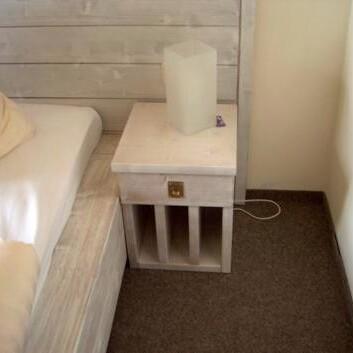 Nachttisch aus weißem Holz Kleiner Nachttisch mit Schublade, Lampe und offener Ablage neben weißem Holzbett