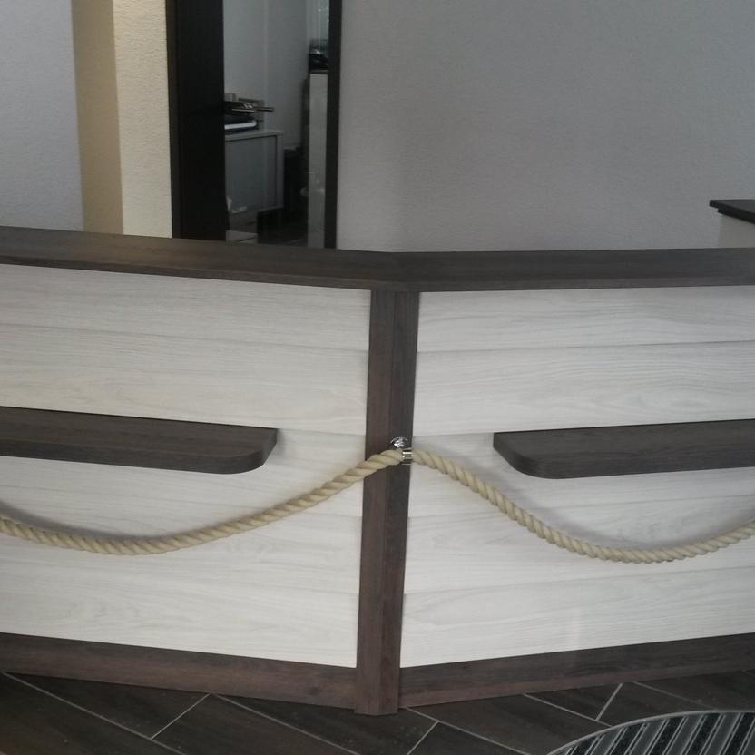 Empfangstresen Tischlerei Brüsch Empfangstresen mit weißer Front, umrahmt von dunklem Holz und mit davor gespanntem Seil