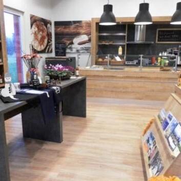 Moderner Hofladen mit Verkaufstheke Hofladen mit Holztheke, schwarzen Lampen, Regalen und regionalen Produkten auf Auslagetischen