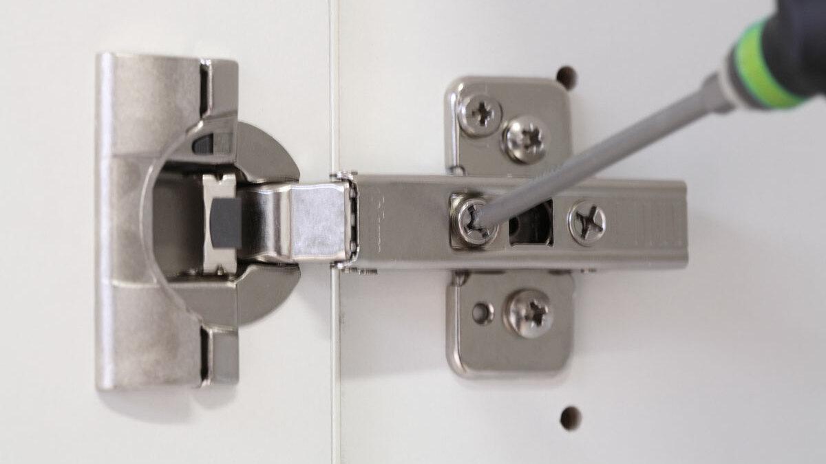 Detailaufnahme eines nachjustierbaren Türscharniers Detailaufnahme eines mit Schraubendreher nachjustierbaren Türscharniers